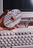 Photograph of hand holding CD disk near keyboard and monitor.
